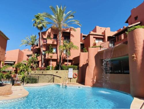 einem Pool vor einem Gebäude mit Palmen in der Unterkunft Lovely Elviria Apartment 200m from the beach in Marbella