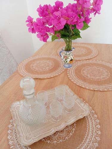 a table with a glass plate and a vase with purple flowers at Vasiliki Skyros Castle View in Skiros