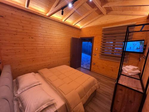 a bedroom with a bed in a wooden room at HOTEL MEGNIAR in Lushnjë