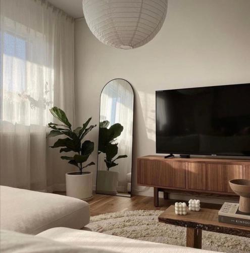 un soggiorno con TV a schermo piatto su un centro di intrattenimento in legno di Leilighet a Larvik
