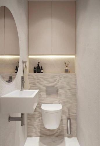 bagno con lavandino, servizi igienici e specchio di Leilighet a Larvik