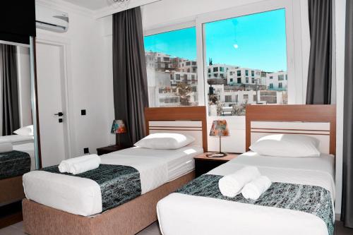 two beds in a hotel room with a window at AirPort villa kayacık in Dalaman