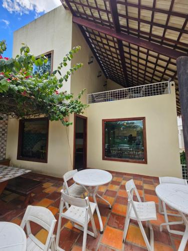 a patio with white tables and chairs in front of a building at Pousada dos Filhos in Arcoverde