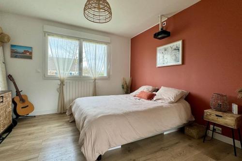 une chambre avec des murs orange et un lit et une guitare dans l'établissement Villa Lorenssia entre Paris et Disney avec jacuzzi, à Lésigny