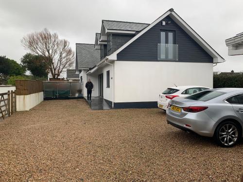 Un hombre parado afuera de una casa con dos autos estacionados. en Ashwood bed and breakfast, en Truro
