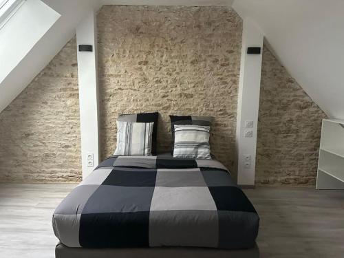 Cama grande en habitación con pared de ladrillo en La Verdière, en Cesny-Bois-Halbout