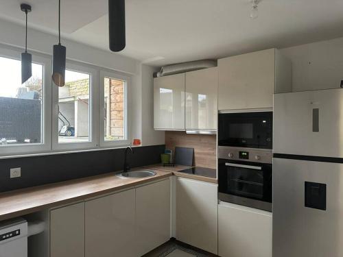 une cuisine avec des armoires blanches, un évier et un micro-ondes dans l'établissement La Verdière, à Cesny-Bois-Halbout