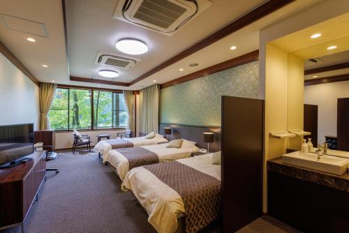 ein Hotelzimmer mit 3 Betten und einem Waschbecken in der Unterkunft Okutamaji in Ome