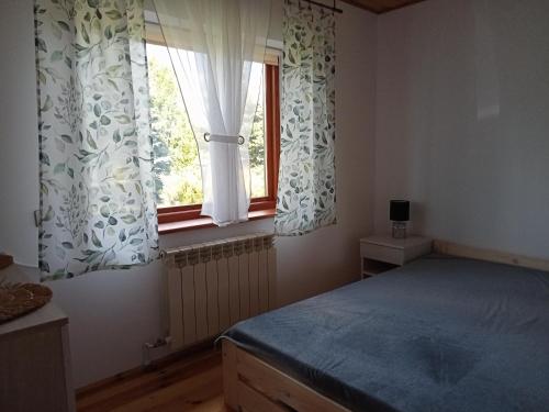 a bedroom with a bed and a window with curtains at Dom na skraju lasu in Płaska