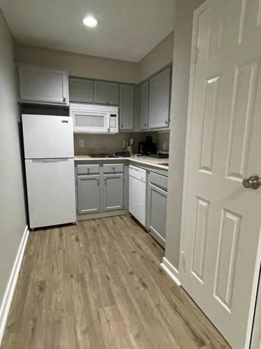 a kitchen with white appliances and a wooden floor at Aksarben Gem- WFH corner desk & minutes from I-80 in Omaha