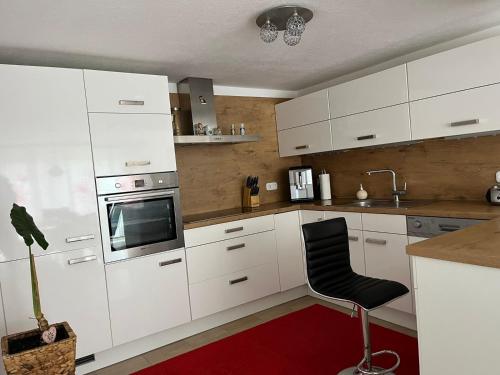a kitchen with white cabinets and a black chair at Charmantes Ferienhaus - Velden in Fahrendorf