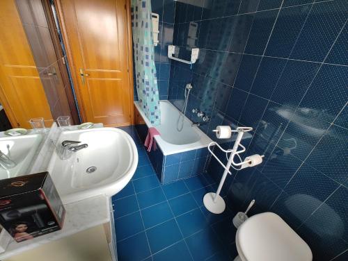 Baño azul con aseo y lavamanos en Giardinetti Rooms, en Roma