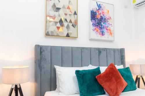 a room with a bed with pillows and paintings on the wall at Serenity Haven - Gated Pool WiFi Sea View in Agblesia