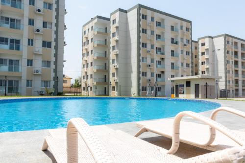 a swimming pool with two apartment buildings in the background at Serenity Haven - Gated Pool WiFi Sea View in Agblesia