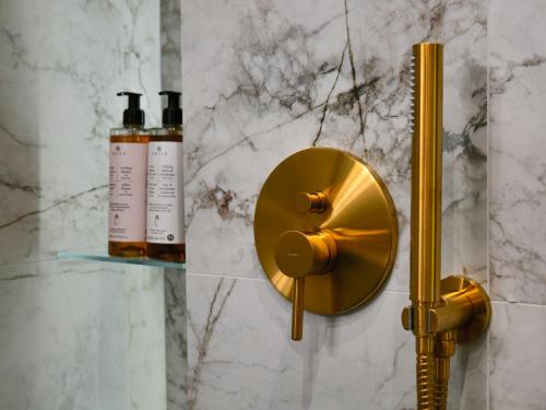 a shower with a gold shower head and two bottles at Sage Apartment in Kraków