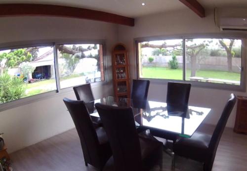 une salle à manger avec une table, des chaises et des fenêtres dans l'établissement Maison Les Cailloux, à Beaucaire