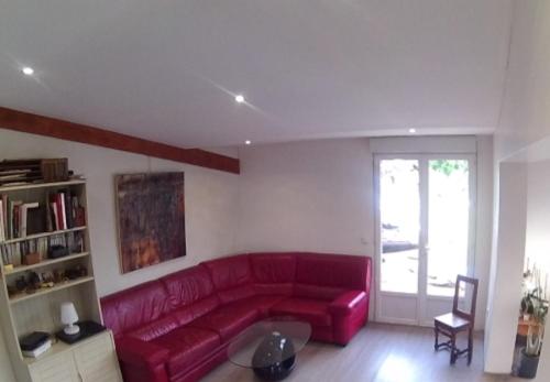 un canapé rouge dans un salon avec une fenêtre dans l'établissement Maison Les Cailloux, à Beaucaire