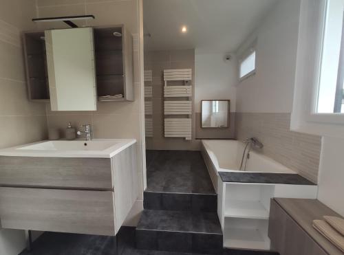 une salle de bain avec un lavabo et une baignoire dans l'établissement Maison avec Jardin - 10 pers - Proche Paris Disney & Golf - Idéal Pro & Familles, à Lésigny