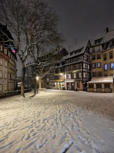 una calle cubierta de nieve en una ciudad por la noche en Chambre dans appartement en Colmar