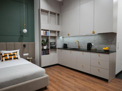 a bedroom with a bed and a kitchen with white cabinets at Sage Apartment in Kraków