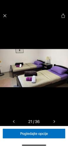 três camas num quarto com almofadas roxas em Dody apartmani em Leskovac