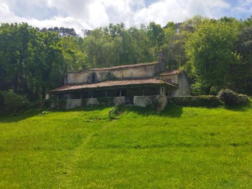 an old building in a field of green grass at Su3ño Cántabro apto en Unquera in Unquera