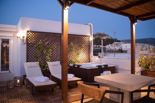 um pátio com uma mesa, cadeiras e comodidades para churrascos em Private Rooftop - Acropolis view - Jacuzzi - Metro em Atenas