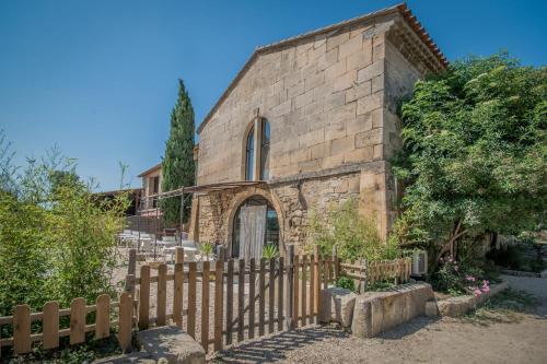 un ancien bâtiment en pierre avec une clôture en bois dans l'établissement B&B Maison d'hôte et gite Mas d'Eymard, à Arles