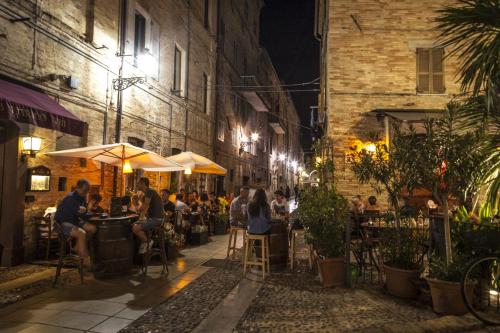 a group of people sitting at tables in an alley at night at PROMO- 100 mt dal Mare- Relax-WiFi & AC in Porto San Giorgio