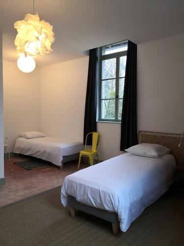 Cette chambre comprend deux lits, une fenêtre et un lustre. dans l'établissement Domaine de l'Ile, à Boulleret