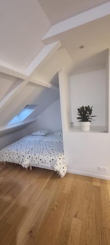 Habitación blanca con cama en el ático en Appartement pré de Paris, en Gagny