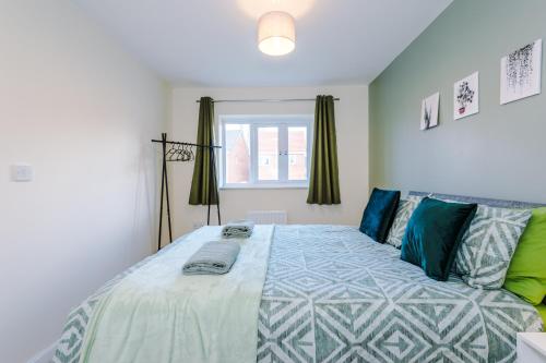a bedroom with a large bed with blue and green pillows at Modern Semi detached in a quiet location, Driveway parking in Ewloe