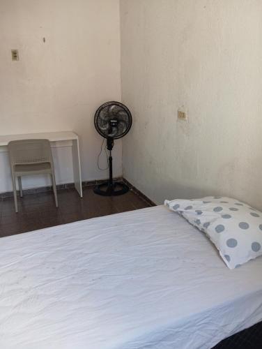 a bedroom with a white bed and a fan at Hostel Teresina in Teresina