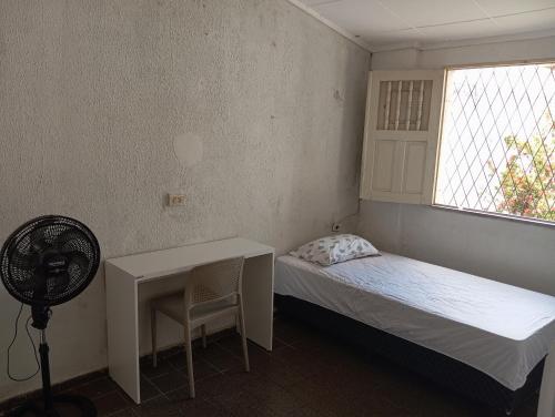 Schlafzimmer mit einem Bett, einem Schreibtisch und einem Fenster in der Unterkunft Hostel Teresina in Teresina