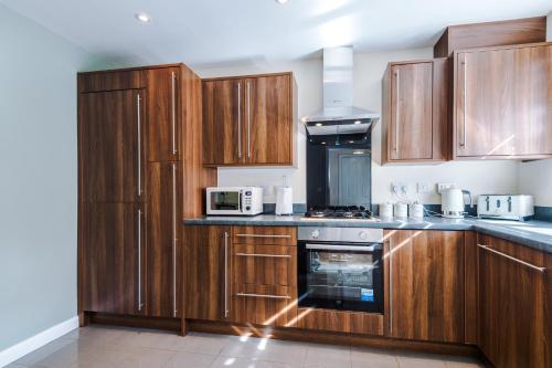 a kitchen with wooden cabinets and a stove top oven at Modern Semi detached in a quiet location, Driveway parking in Ewloe