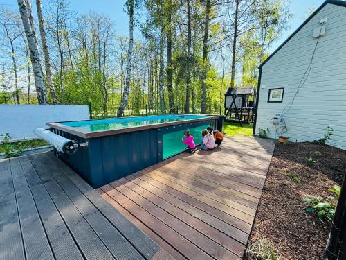 two children sitting in front of a swimming pool at Domy nad morzem- Family Resort - Chata Pirata 2 in Dziwnów