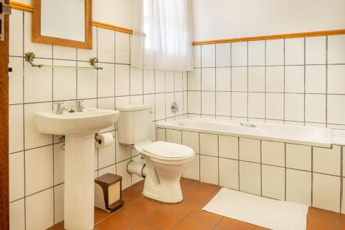 a bathroom with a toilet and a sink and a tub at Karoo Country Inn in Middelburg