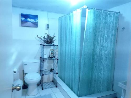 y baño con cortina de ducha azul y aseo. en Linda habitación cerca al mar, en Lima