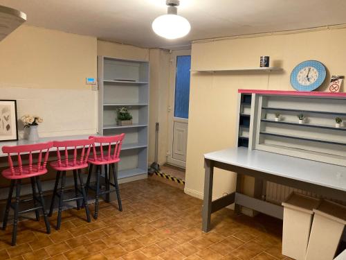 una cocina con taburetes rojos y una mesa y estanterías en Pink door house in Clifden, en Clifden