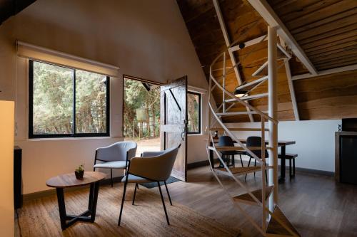 Zimmer mit einer Wendeltreppe, Stühlen und einem Tisch in der Unterkunft EyB Chalets in Heredia