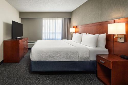 a hotel room with a bed and a television at Courtyard by Marriott Fort Collins in Fort Collins