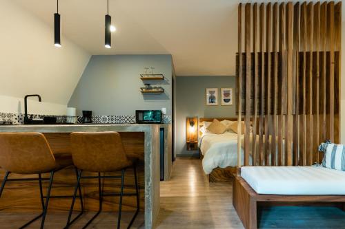 ein Hotelzimmer mit einem Bett und einer Bar mit Stühlen in der Unterkunft EyB Chalets in Heredia