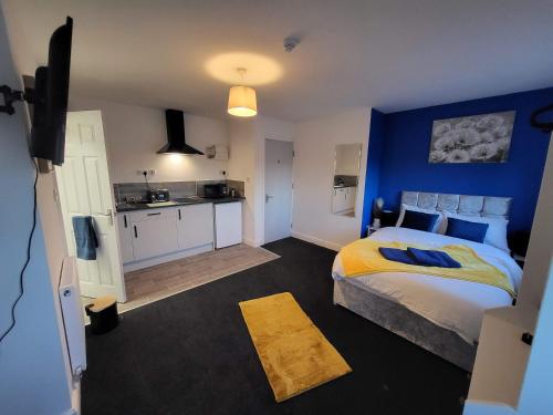 een slaapkamer met een bed en een blauwe muur bij Premier Nottingham Studios - Burford Road in Nottingham