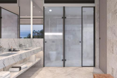 a bathroom with two sinks and a glass door at The Bodrum EDITION in Yalıkavak