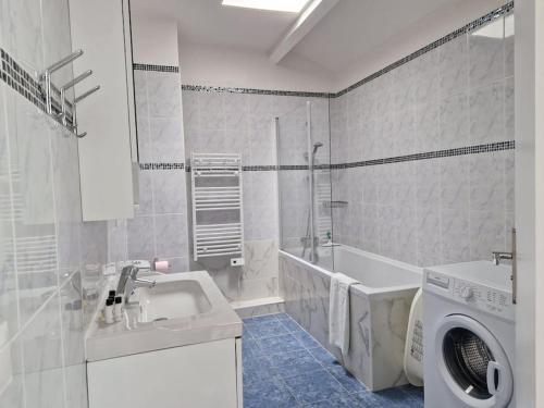 une salle de bain blanche avec une machine à laver et un lavabo dans l'établissement WD Saint Roch - Appartement Duplex 202 - Métro 7 Proche Paris, à Villejuif