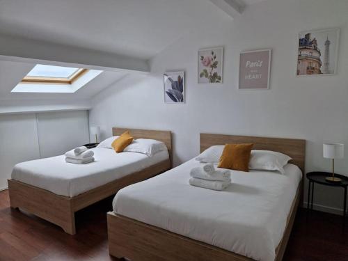 une chambre avec deux lits avec des serviettes dessus dans l'établissement WD Saint Roch - Appartement Duplex 202 - Métro 7 Proche Paris, à Villejuif