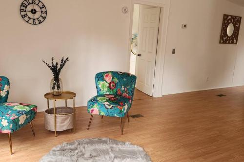 a living room with two chairs and a table and a clock at Sea Island Seclusion Marsh View with Beach Pass in St. Helena Island