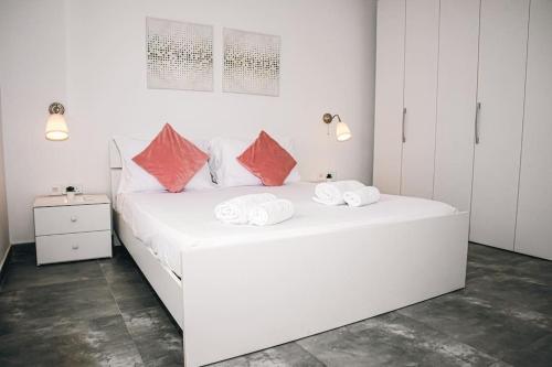 a white bedroom with a large white bed with red pillows at Birzebbuga -Two Bed Penthouse in Birżebbuġa