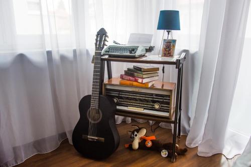 a guitar sitting on a stand next to a table with a lamp at Alen Apartment Old town - Free Parking in Sarajevo