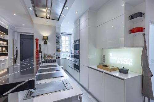 une cuisine avec des armoires blanches et un comptoir dans l'établissement Sublime appartement climatisé proche Paris et Boulogne, à Neuilly-sur-Seine